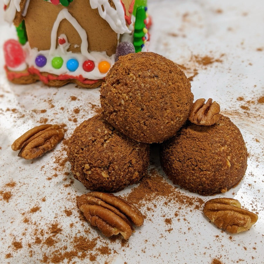Gingerbread Bites stacked in front of a gingerbread house