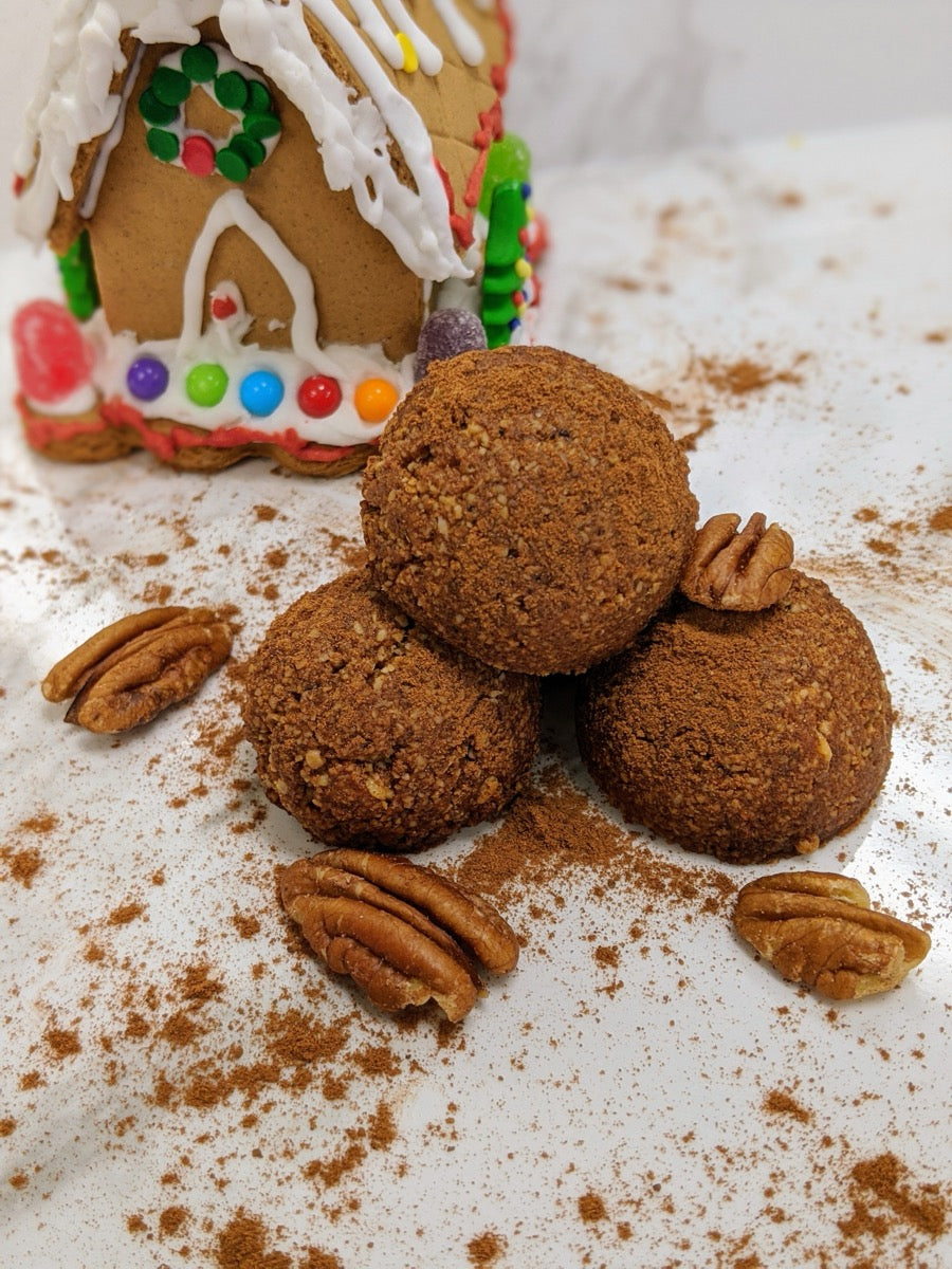 Gingerbread Bites stacked in front of a gingerbread house with pecans and spice