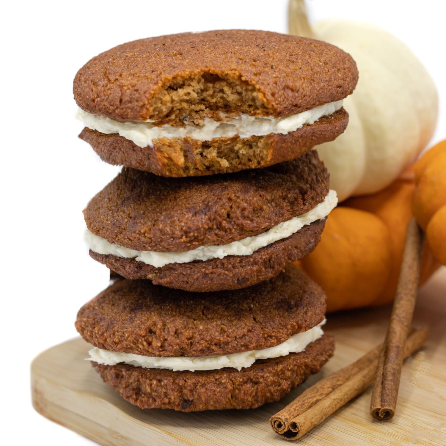 Stack of three Pumpkin Spice keto cookie sandwiches with cinnamon sticks