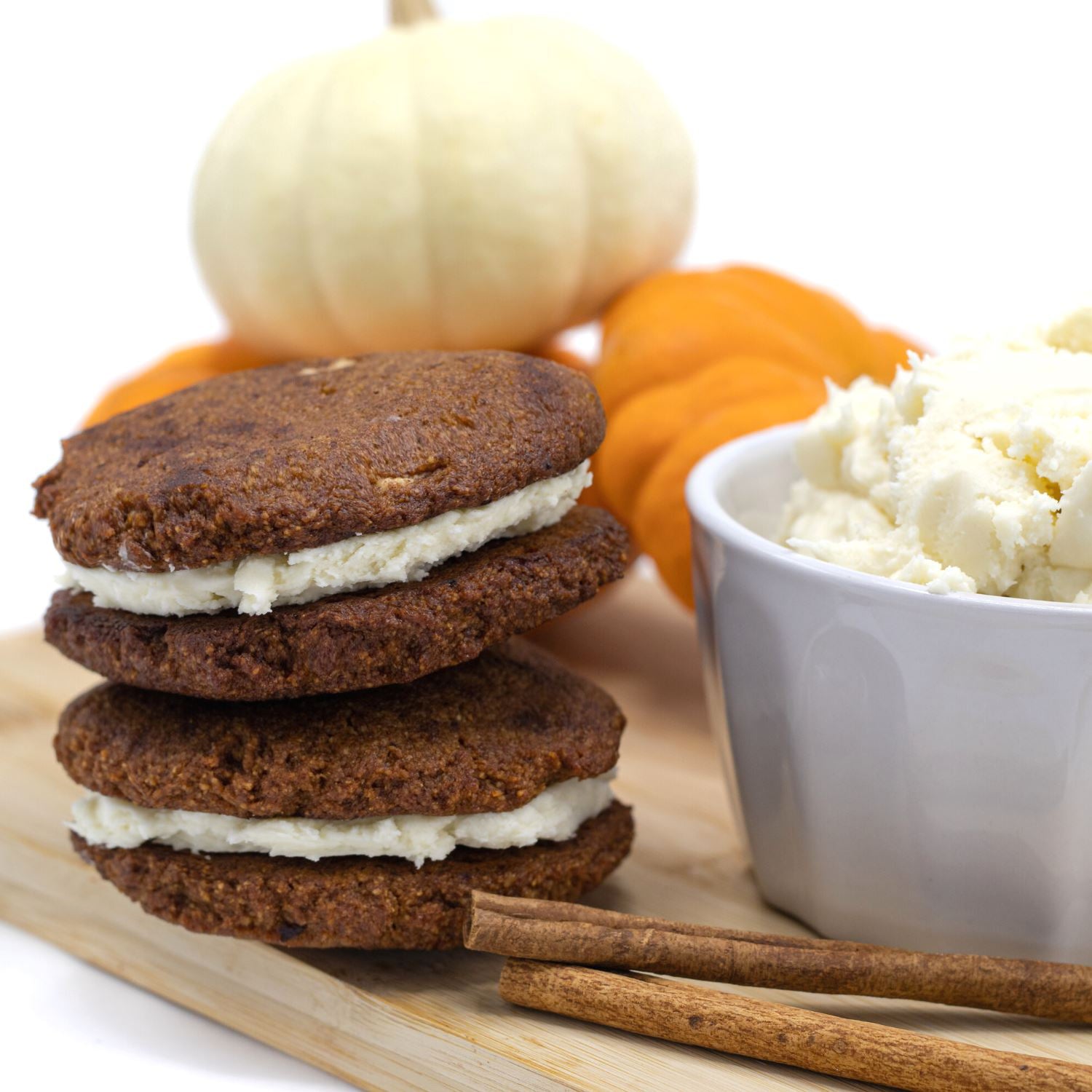 Pumpkin Spice keto cookie sandwiches with a bowl of cream cheese frosting